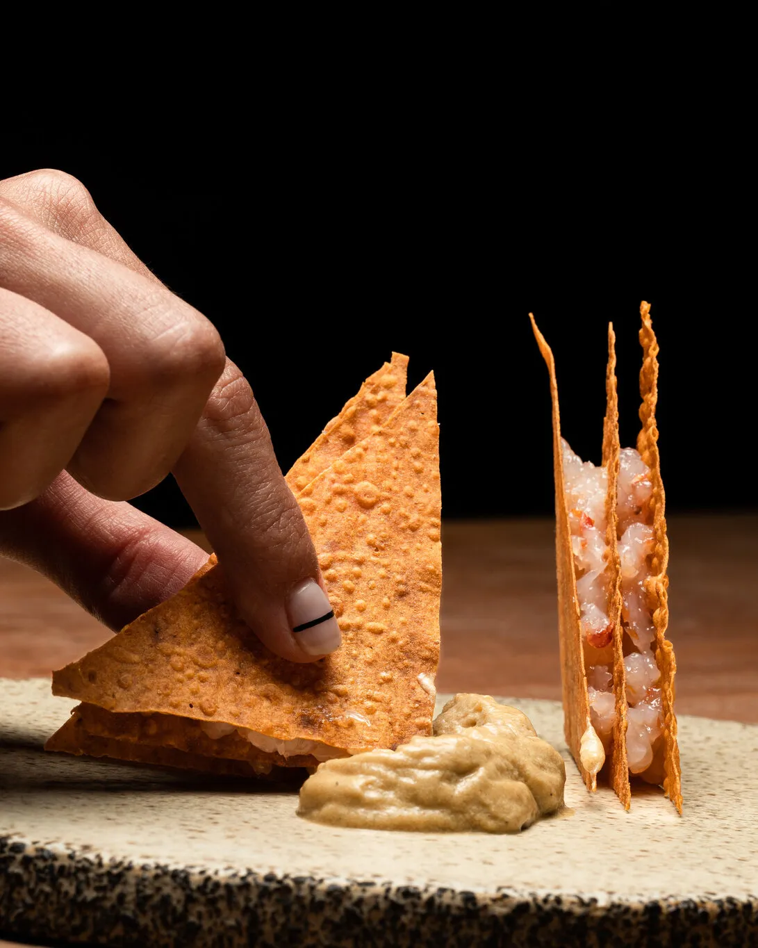 Mano montando una tosta sobre fondo negro
