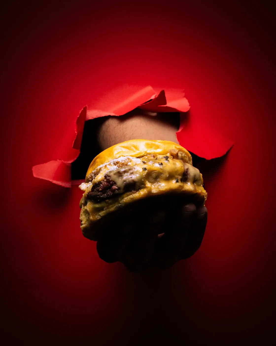 Burger bursting through red paper