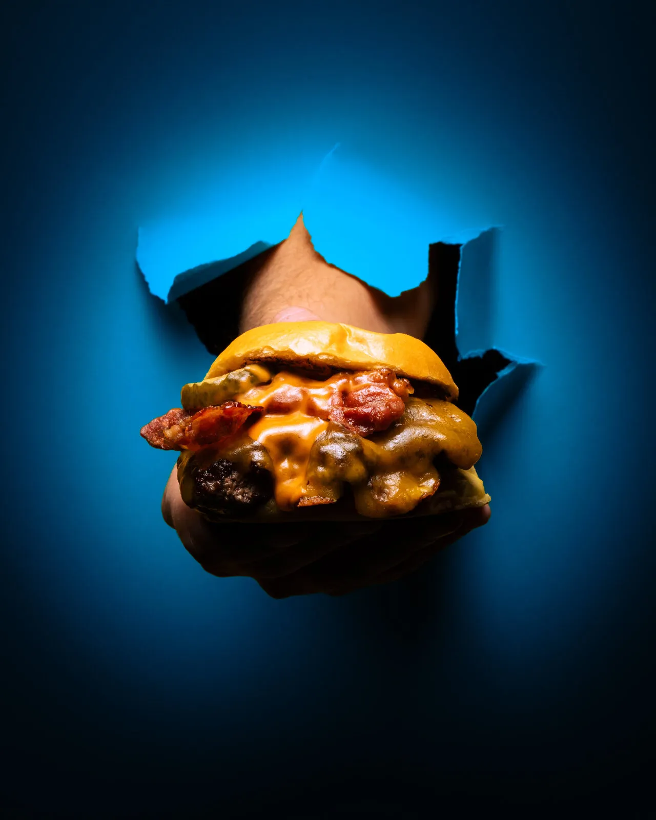 Burger bursting through blue paper