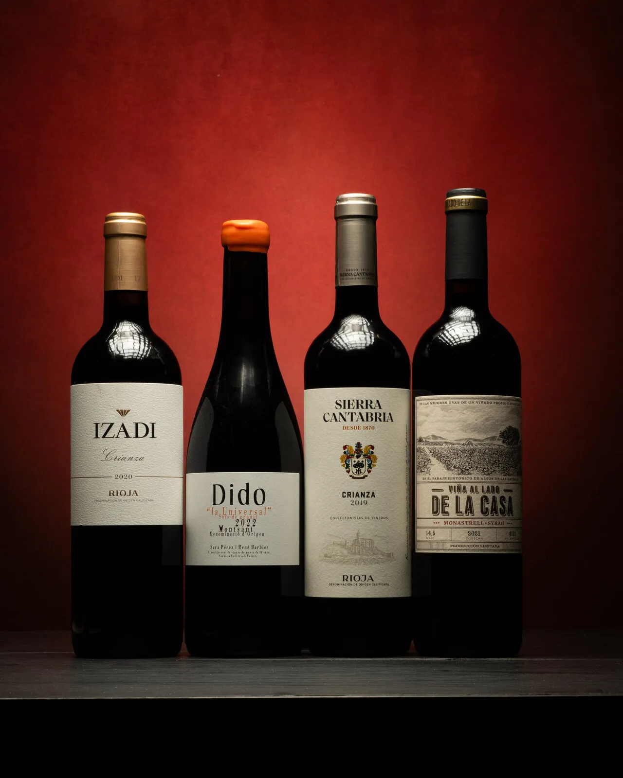 Four bottles of red wine on a red background