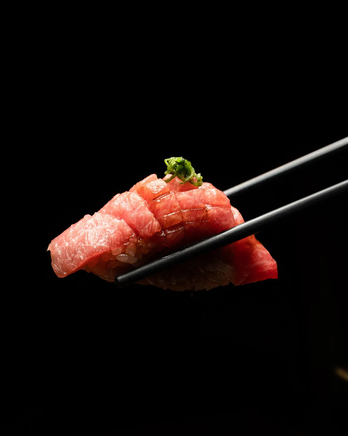 Tuna nigiri held with chopsticks